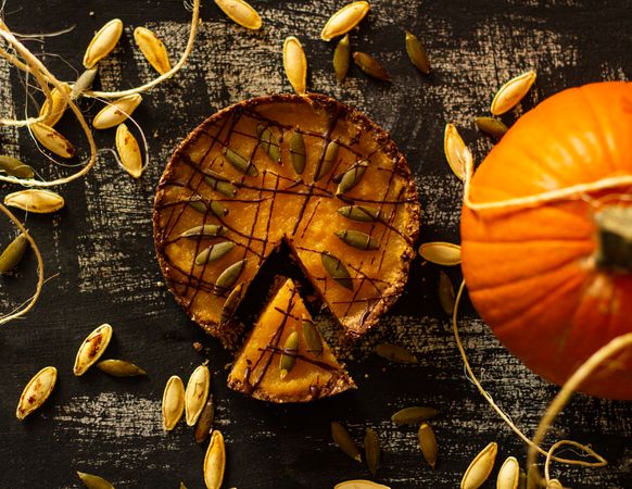 Sliced pumpkin pie beside pumpkin